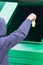 A boy in a blue hooded jumper throws an Apple stub into a green dumpster