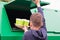 A boy in a blue jumper, throws disposable glasses into a dumpster, close-up, rear view