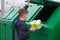 The boy in the blue jumper, throws out the empty disposable cups in the green bin container