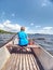 Boy in blue with life jackets at legs floats on vessel boat