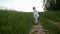 Boy in blue pants and a white jacket in a hood runs along the road