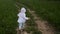 Boy in blue pants and a white jacket in a hood runs along the road