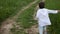 Boy in blue pants and a white jacket in a hood runs along the road