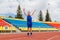 A boy in a blue sports uniform jumps at a sports stadium. empty stands