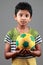 Boy with body smeared with mud holds a football