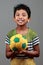 Boy with body smeared with mud holds a football and shows energy