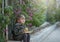 a boy with a book and an apple sits at the fence with a lilac bush