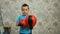 A boy in boxing gloves beats a punching bag.