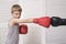 Boy in boxing gloves fights with a man`s hand in a glove.