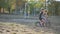 The boy with brother rides on a runbike in the park in summer sunny weather having a good mood