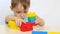 A boy builds out of colored blocks of a constructor at a table on a white background.