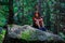 Boy in Camouflage Hat and Vest Sitting on a Boulder.