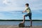 Boy catches fish with a fishing rod on a lake against the background of a beautiful sky, side view