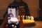 Boy celebrate birthday with white birthday cake with colorful candles,  view through the screen of mobile