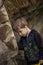 A boy-child on the background of a rocky mountain looks at something with curiosity and is surprised. Nature, rocks, mountains