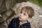 A boy-child on the background of a rocky mountain looks at something with curiosity and is surprised. Nature, rocks, mountains