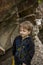 A boy-child on the background of a rocky mountain looks at something with curiosity and is surprised. Nature, rocks, mountains