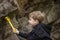 A boy-child on the background of a rocky mountain looks at something with curiosity and is surprised. Nature, rocks, mountains