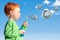 Boy child blowing soap bubbles into sky