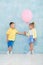 Boy child gives a balloon to a girl. Signs of attention, sympathy and courtship.