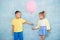 Boy child gives a balloon to a girl. Signs of attention, sympathy and courtship.