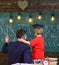 Boy, child in graduate cap listening teacher, chalkboard on background, rear view. Preparation for school concept