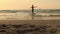 Boy child is jumping on a sea beach at sunset. Hyperactive boy run and jump on beach sand smiling.