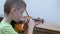 Boy child practicing playing violin in music lesson at musical class at school.