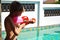 Boy child shoots with a water pistol. Water active games at the pool