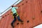 Boy child steps on the ledges on the vertical wall on the obstacle course in the amusement park, outdoor activities, rock climbing