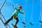 Boy child steps on wooden boards on the obstacle course in an amusement park, outdoor activities, rock climbing, danger, training,