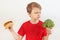 Boy chooses between fastfood and broccoli on white background