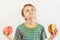 Boy chooses between fastfood and healthy diet on white background