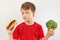 Boy chooses between fastfood and vegetable on white background