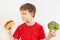Boy chooses between hamburger and broccoli on white background