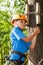 Boy with climber equipment intently keeps rope