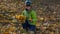 Boy collecting bouquet with yellow leaves in park