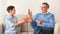 Boy Congratulating Grandpa Giving Gift Sitting On Couch Indoor