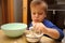 Boy cooking sweets with flour and saucer holding shape