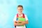 Boy with copybooks and backpack against color background