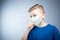 The boy coughs in his hand. A child in an antiviral mask