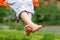 Boy crossed his bare feet. Closeup of feet happy kid sitting and swinging, sunny summer day, countryside background