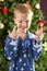 Boy Crossing Fingers In Front Of Christmas Tree