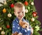 Boy Cuddling Teddy Bear In Front Of Christmas Tree