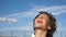 A boy with curly hair breathes deeply and smiles. Close sunny portrait against a blue sky. Post Quarantine Life