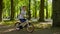 Boy cycles with spinning colorful windmill on bike along path among green trees in park