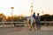 Boy with disabilities riding horse at equestrian center at sunset.