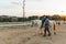 Boy with disabilities riding a horse during equine therapy session outdoors.