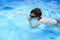 Boy dives in swimming pool with swimming glasses. boy swims in the pool.