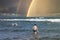 Boy with diving father in the swimming flippers above the storm waves on the rainbow background